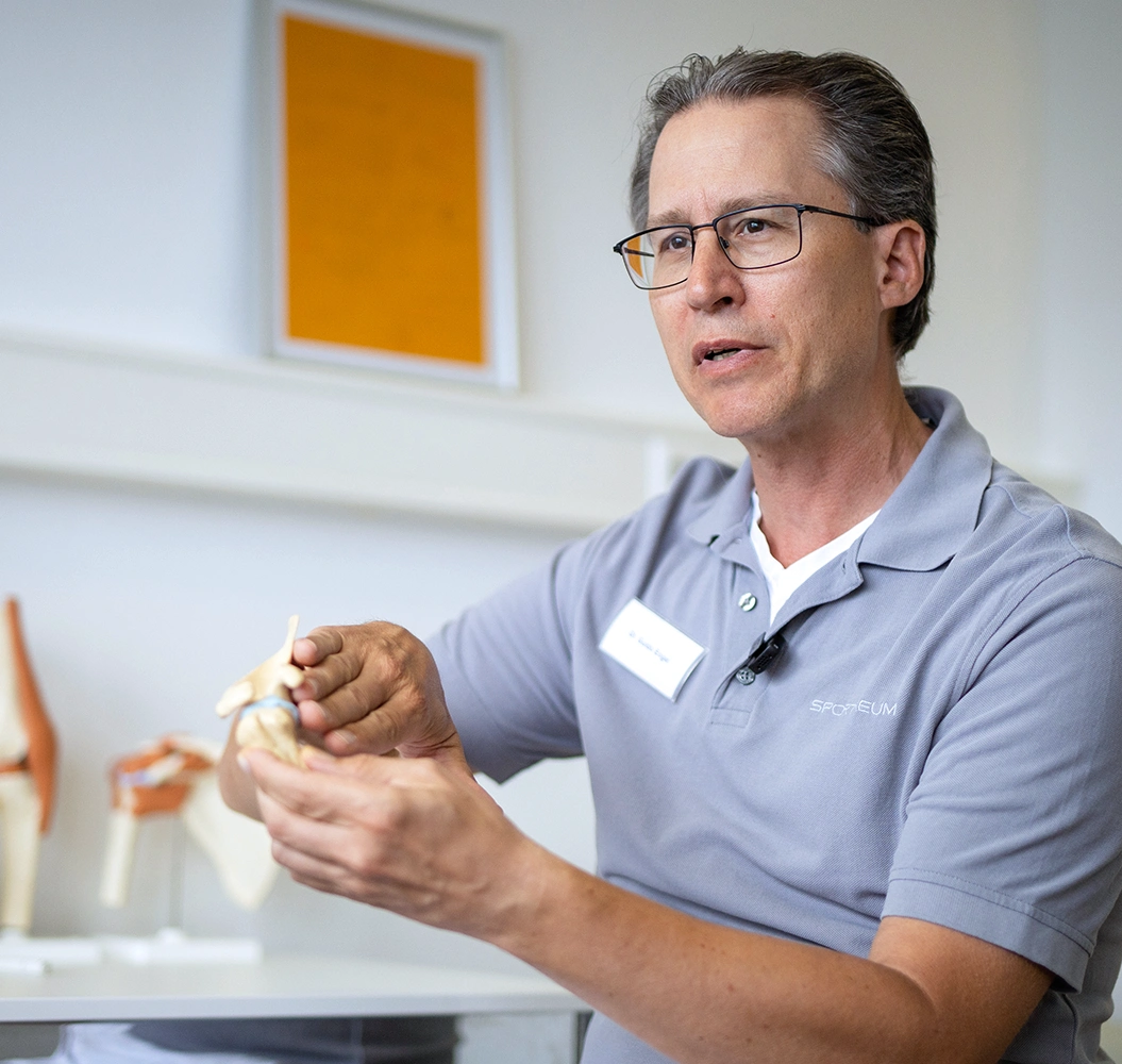 Sportheum_Sportklinik_Fellbach_Leistungen_Rehabilitation Arzt der Sportheum Sportklinik Fellbach erklärt mit einem anatomischen Modell den Ablauf der Rehabilitation – individuelle Betreuung für eine erfolgreiche Genesung.